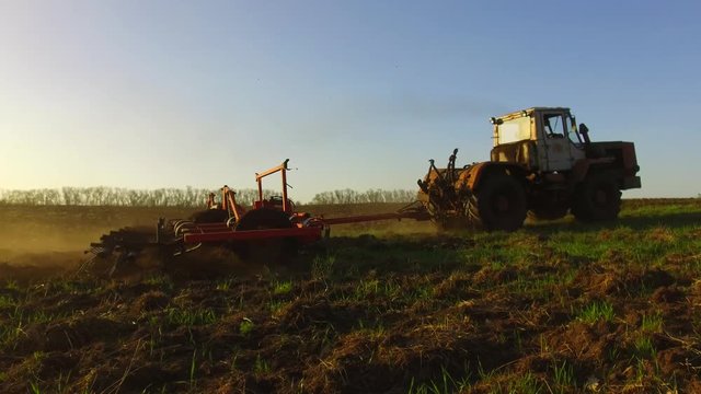 Farmer in tractor soil plows steadicam motion agriculture the ground Russia preparing land with seedbed cultivator as part of lifestyle pre seeding activities in early spring season of agricultural