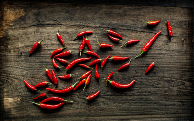 Bird's eye chili peppers on dark wooden background in overhead view