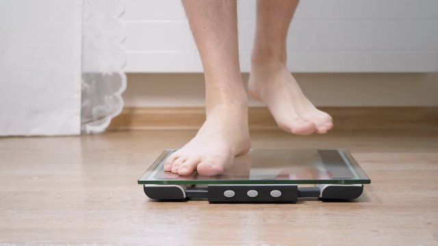Man step on digital glass scales to check his weight