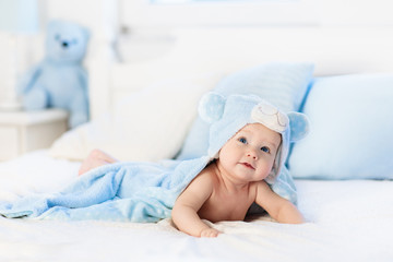 Obraz na płótnie Canvas Baby boy in blue towel on white bed