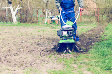 Man working in the spring garden with tiller machine