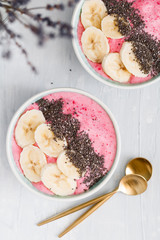 Top view of summer smoothie bowl with strawberry, banana and chia seeds over white background. The concept of vegan and healthy food. Copy space.