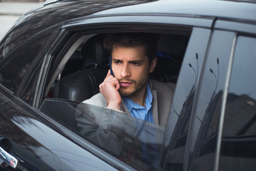 Financially-minded! Closeup portrait of the handsome serious young businessman talking on smartphone, while going to the airport by taxi.