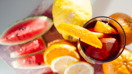 Glass of sangria wine on a natural background surrounded by fresh fruit, citrus, strawberry,...