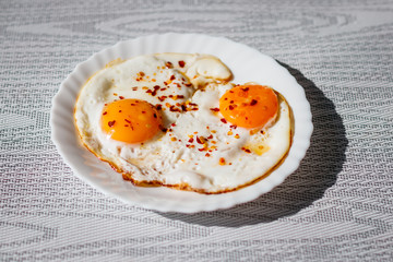 Fried eggs on a plate with chili peper.