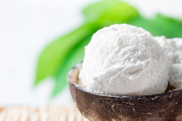 Delicious Vegan Coconut Ice Cream in Bowl on Wicker Table. Green Palm Leaves Tropical Plants Background. Plant Based Diet Healthy Dessert Superfoods. Vacation Concept. Copy Space
