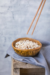 Bowl with wild brown mixed rice on the wooden background, wabi sabi style