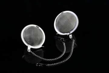Two tea strainer on a chain isolated for black background.