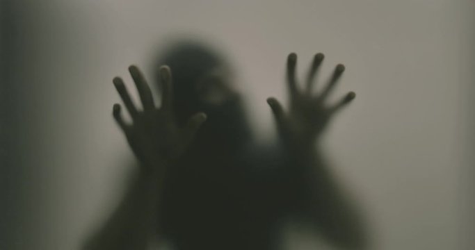 Shadowy figure behind glass / fear, panic concept