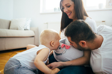 A happy family is having fun with your little child on the floor. Pregnant woman and her husband in the expectation of the birth of a new baby.