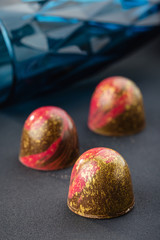 Handmade candy with red and gold splashes on black background. Exclusive handcrafted bonbon