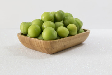 Green cherry-plum in wooden bowl