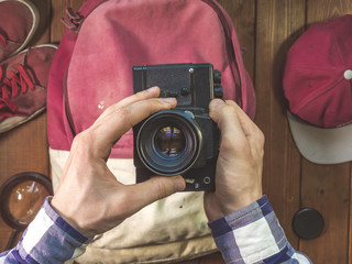 travel concept with vintage camera in the hands and backpack on a wooden surface