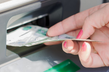 Hand of a man with money, uses an ATM