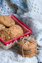 homemade oat cookies with sunflower seeds in and near red checkered basket on white and blue plaid