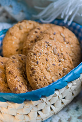 homemade oat cookies with sunflower seeds in and near blue checkered basket on white and blue plaid