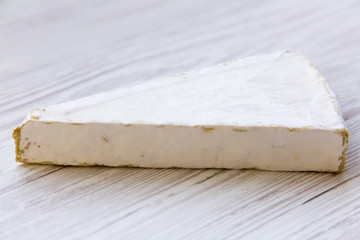 Brie cheese on white wooden table. Side view.