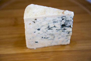 Blue cheese on wooden board. Side view.