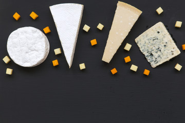 Set of different types of cheese on dark background. Food for romantic. Flat lay. From above, top view. Copy space.