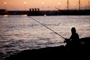 the fisherman at sunset catches fish