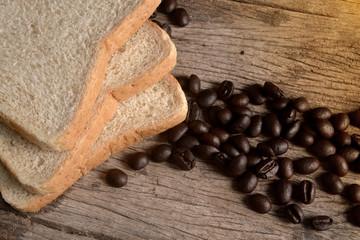 Coffee beans and slice bread on wooden table. Top view.