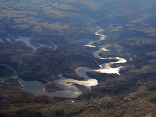 Viewo n a snake-like lake reflecting sunlight from aerial perspective, Germany
