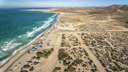 Mar azul y blancas olas playa desértica con palapas