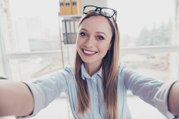 Self portrait of cheerful, positive, charming woman with hairstyle and glasses on head shooting...