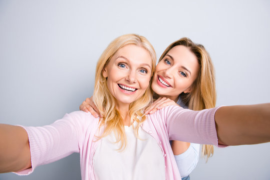 Cheerful positive charming grandma shooting self portrait with trendy stylish granddaughter having leisure casual outfits perfect mood enjoying time together isolated on grey background