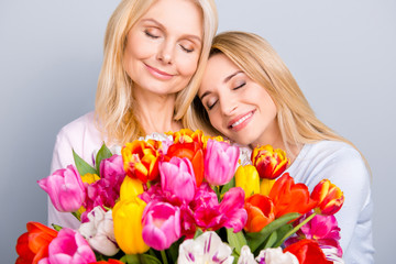 Cheerful lovely cute joyful stylish mom and adult child keeping eyes closed having big bouquet of colorful tulips celebrating 8-march trust support understanding concept isolated on grey background