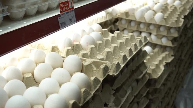Young man shopping for food in the supermarket. He checking the box with eggs. Close up