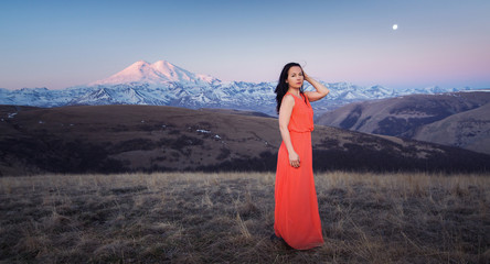 girl in pink dress at sunrise on the background of mountains of Elbrus