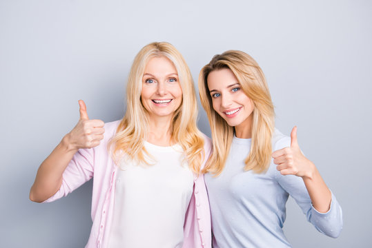 Portrait of charming cheerful hispanic similar mother and daughter with hairstyle beaming smiles gesturing thumbup like symbols isolated on grey background advertisement concept
