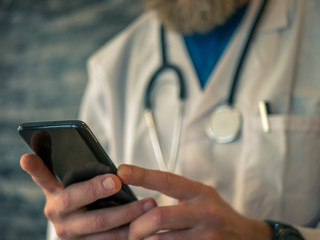 Male doctor is using a smart phone.