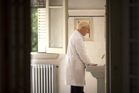 A senior man is washing his hands.
