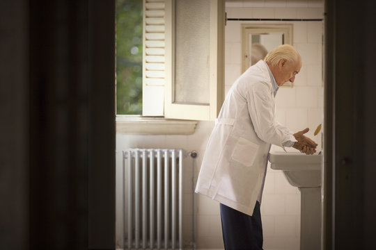 A senior man is washing his hands.