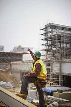 Male construction worker pointing at a building site.