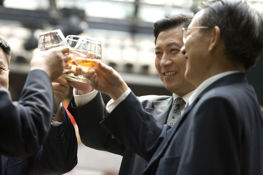 Mid-adult businessmen toasting a drink in a bar.
