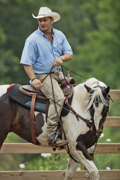 Cowboy riding horse on ranch