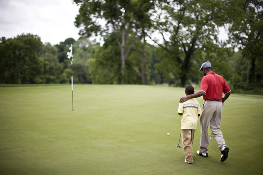 Father and son walking across a golf course