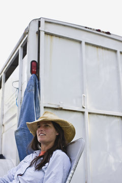 Mid-adult woman sitting beside a horse float.