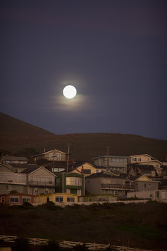 Moon rising above small town at dusk