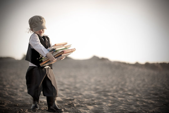 Little Boy In Victorian Era Clothing Carrying Books Along Beach