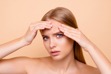 Naklejka premium Sad, upset, charming, pretty, nude, natural girl touching forehead with fingers having dry oiled skin, minerals, vitamins, detox, moisturizing, hydration concept isolated on beige background