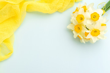 Daffodil bouquet with yellow textile decoration on blue pastel background with copy space.