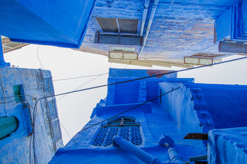View from the bottom to the top of some traditional houses in a small alleyway in the blue city of Jodhpur, Rajasthan, India.