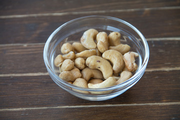 cashews inside glass bowl on a wooden table close up