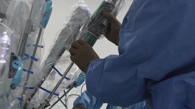 Operating room, team of surgeons prepares patient to cancer removal surgery via Minimally Invasive Robotic Surgery with the Surgical System. Hi-tech medical robot. Close up