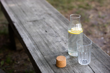A bottle of water with lemon and a glass. A bench on which a refreshing drink is placed.