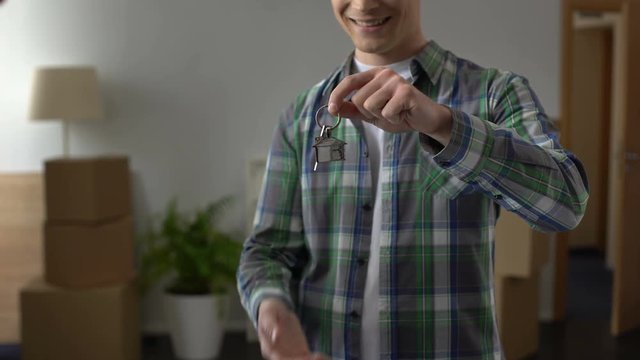 Real estate agent presenting key from new house to young man, youth crediting